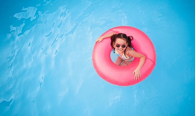 Happy girl swimming in pool in inflatable ring