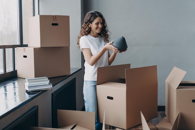 Happy girl unpacking cardboard boxes and taking the vase European woman packing boxes to move