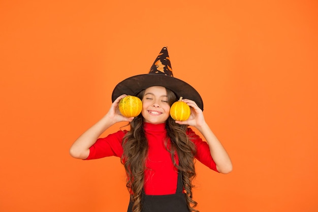 Happy girl in witch hat costume to halloween with small yellow pumpkin halloween jack o lantern