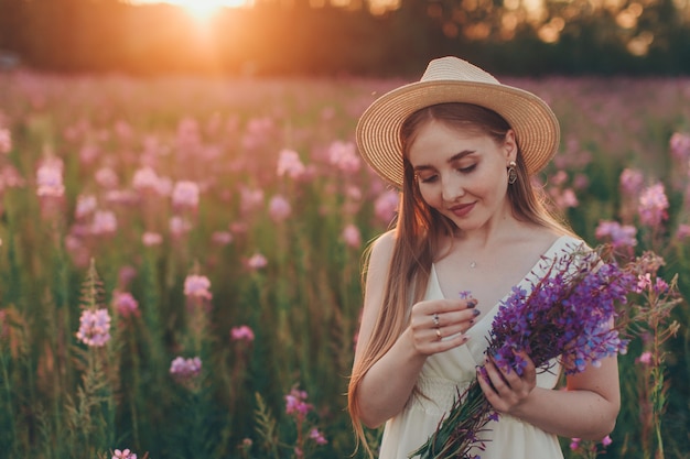 a happy girl with bouquet walks through a flower meadow. Love and spring blooming