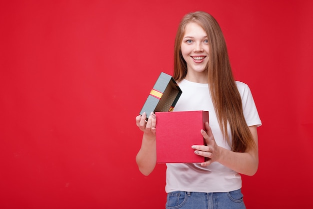 Happy girl with a gift on a red background