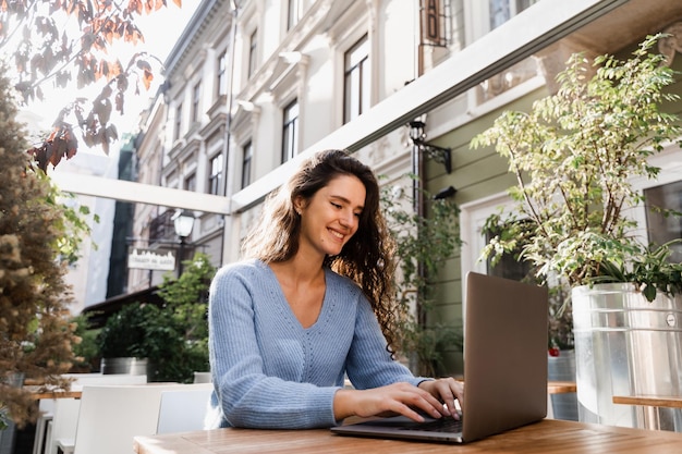 Happy girl with laptop is chatting with her friends and family outdoor in cafe Confident business woman is chatting using laptop with colleagues via video connection and discussing new ideas