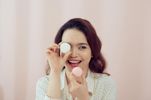 Happy girl with macaron on pink background