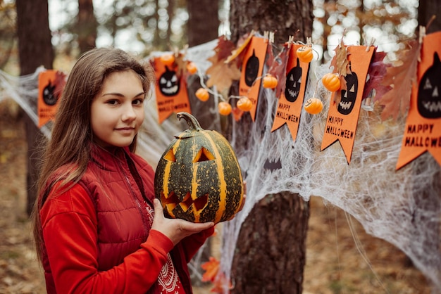 Happy girl with pumpkin in her hands outdoor in autumn park Halloween concept