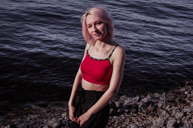 Happy girl with short hair and a red top on the seashore