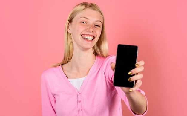 Happy girl with smartphone with empty screen. Advertising new model. Beauty woman shows mobile phone