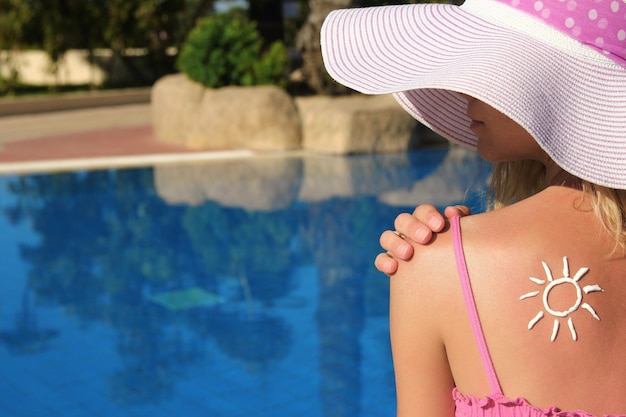 Happy girl with the sun on her back at the pool in the nature