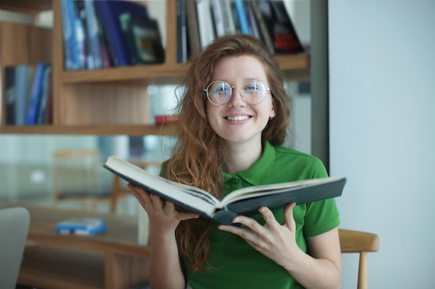 Happy girl young woman read book in library college or university student prepare to exam in glasses