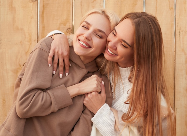 Happy girlfriends in warm clothes hugging together