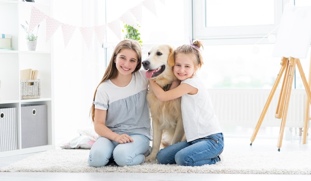 Happy girls friends hugging lovely retriever