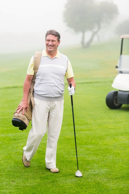 Happy golfer with golf buggy behind 