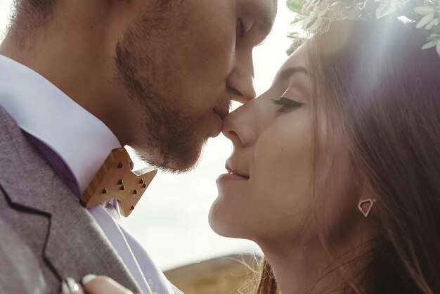 Photo happy gorgeous bride and groom kissing in sun light sensual perfect moment boho wedding couple luxury ceremony at mountains