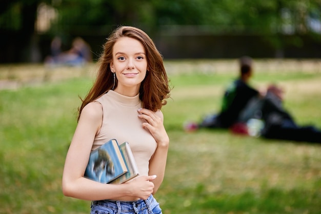 Happy graceful woman with books in hands outside