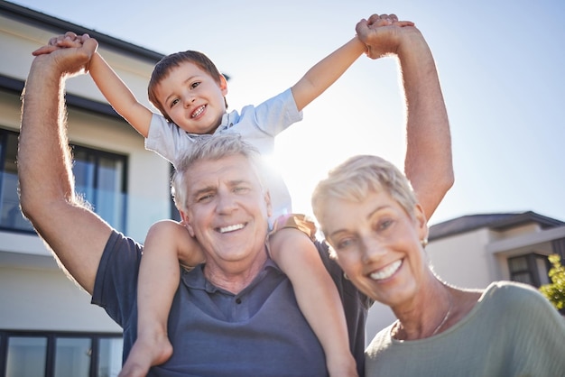 Happy grandparents smile with child outside home and relax in retirement Senior man elderly woman and boy play in garden sun love time together Kid on holiday laughs and create childhood memory