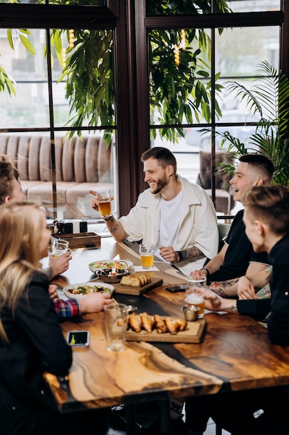 Happy group of friends drinking and clinking with beer and cocktails at brewery bar restaurant