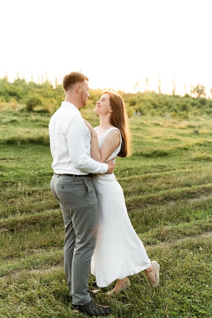 Happy guy hugs his bride at sunset of the day. portrait of a couple in love. happy young people of european appearance. summer honeymoon day