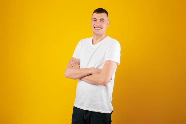 Happy guy posing crossing hands standing on yellow background