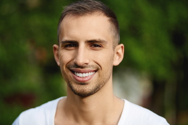 Happy guy in sunglasses posing on a summer day a handsome young man with a broad smile and snowwhite teeth posing outdoors in a casual outfit