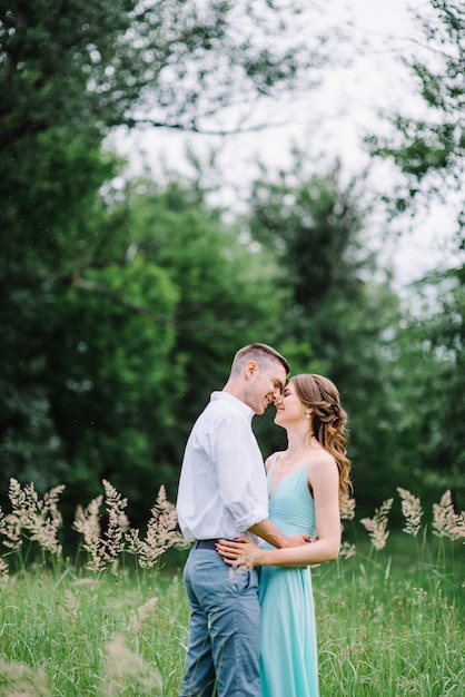 Happy guy in a white shirt and a woman in a turquoise dress are walking in the forest park