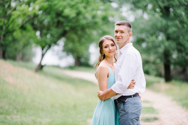 Happy guy in a white shirt and a woman in a turquoise dress walking in the forest park