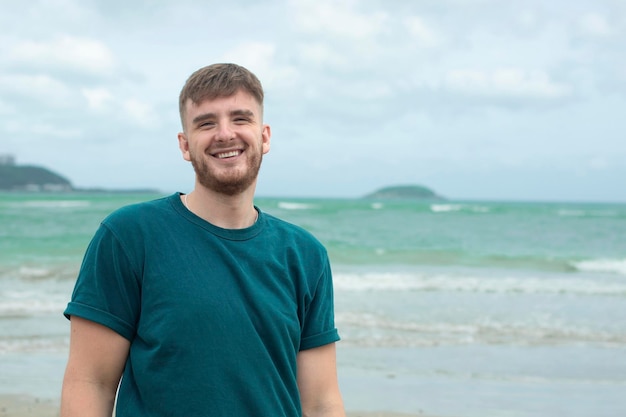 Happy guy young handsome man is enjoying summer vacation at sea beach in tropical exotic country smiling having fun