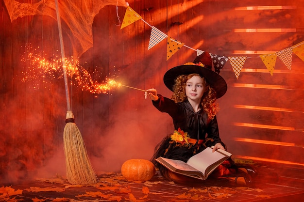 Happy Halloween Cute cheerful little witch with a magic wand and a book of spells conjures