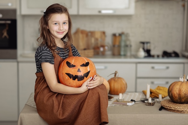 Happy halloween Cute little girl in witch costume with carving pumpkin Happy family preparing for Halloween