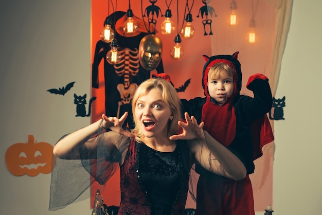 Happy halloween family with pumpkins on a halloween background. Halloween dresses on mother and son