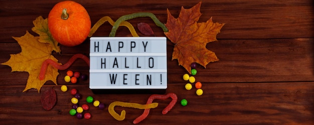 Happy Halloween Festive candies and pumpkins on wooden background