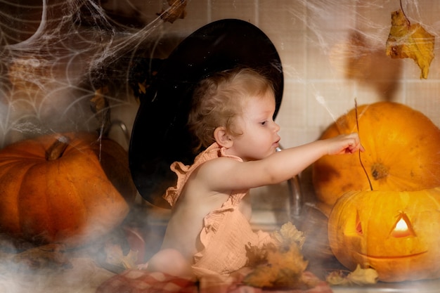 Happy Halloween. Girl in a witches hat and a suit holding a pumpkin.