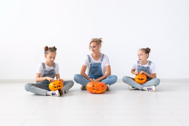 Happy halloween and holidays concept - A mother and her daughters with pumpkins. Happy family