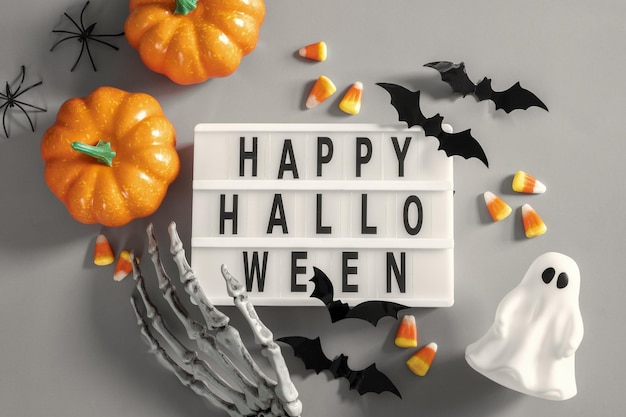 Happy halloween lightbox sign board with pumpkin bats and candy on a grey background