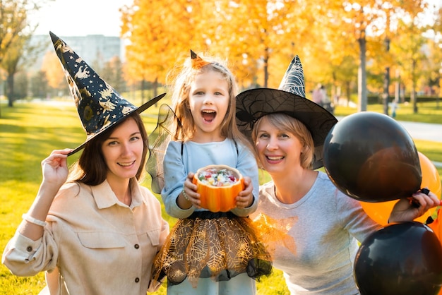 Happy halloween mother grandmother and daughter are having fun at the holiday autumn party orange pumpkin balloons