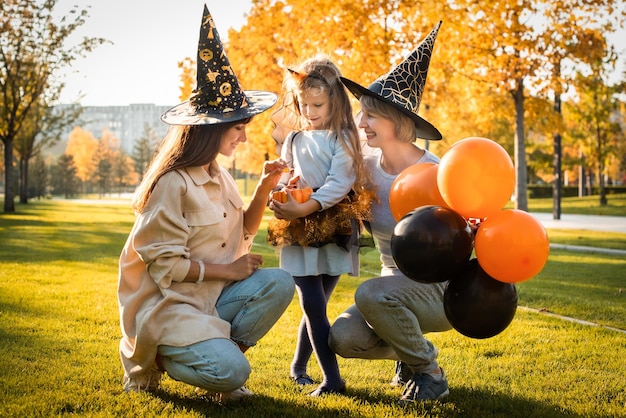 Happy halloween mother grandmother and daughter are having fun at the holiday autumn party orange pumpkin balloons