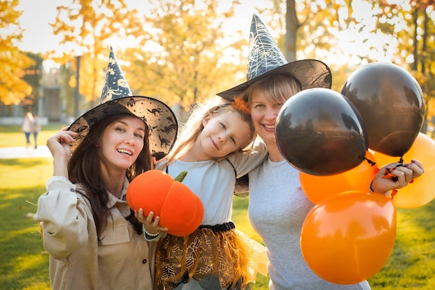 Happy halloween mother grandmother and daughter are having fun at the holiday autumn party orange pumpkin balloons