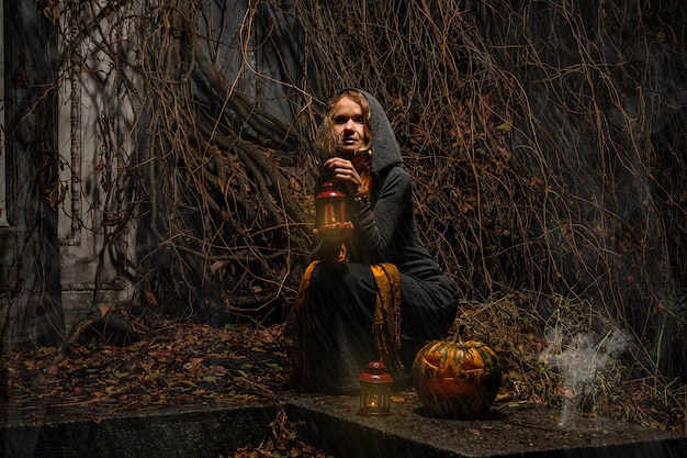 Happy Halloween A pretty witch with a big pumpkin Beautiful young in a witch costume on an abandoned place with a fanatic