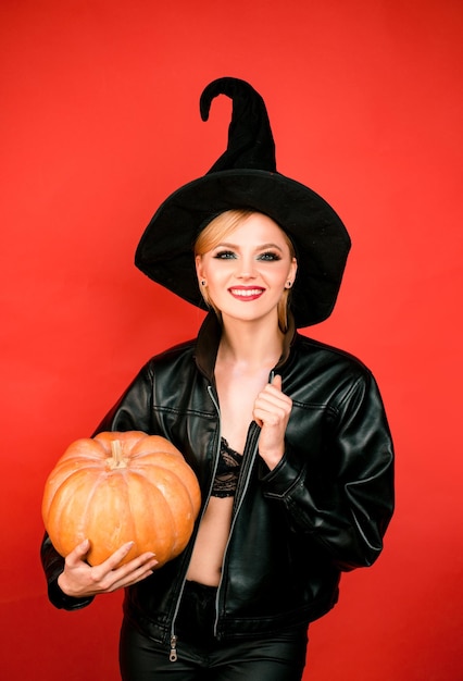 Photo happy halloween young women in black witch halloween costumes on party over red background