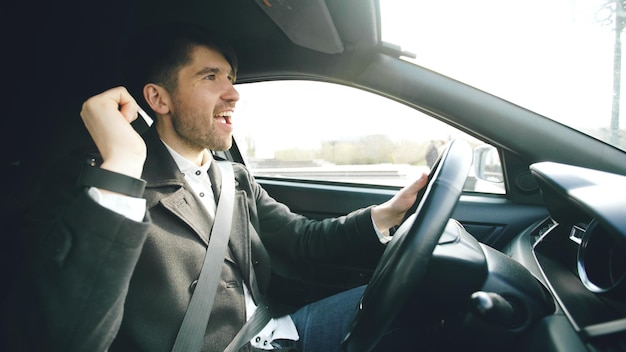 Happy handsome businessman driving car and singing Man is happy after making deals and drives home