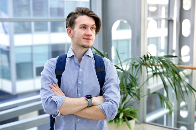 Happy handsome guy young man student at college or university with his hands crossed with backpack