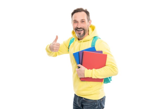 Happy handsome mature man with beard in hoody carry backpack hold notepad or workbook for education isolated on white thumb up