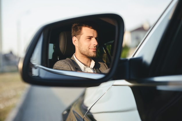 Happy handsome young business man driver in his car