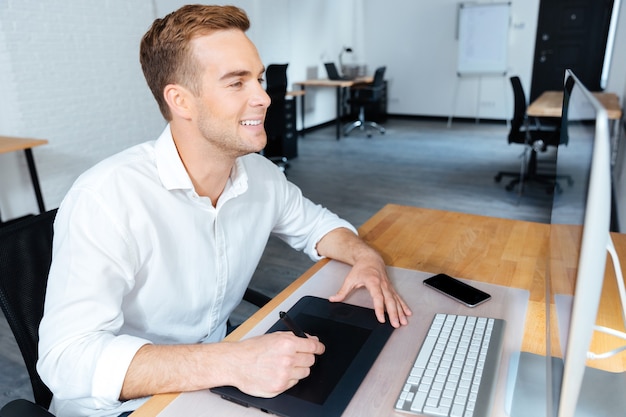 Happy handsome young male designer using computer and