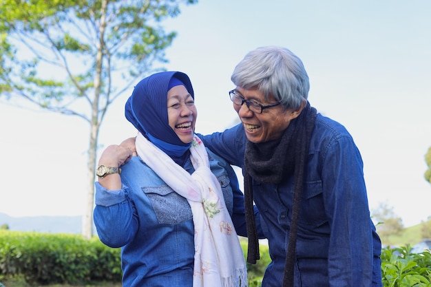 Happy and healthy Asian elderly couple laughing each other at tea plantation