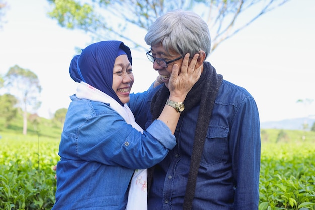 Happy and healthy elderly couple laughing at tea plantation White teeth smile Never ending love