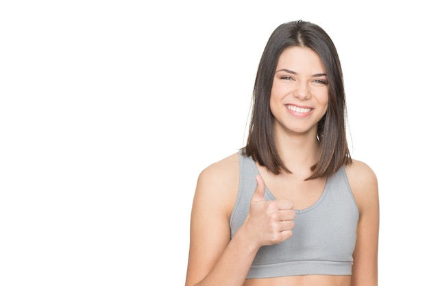 Happy and healthy. Portrait of an attractive female in sports clothing showing thumbs up isolated on white