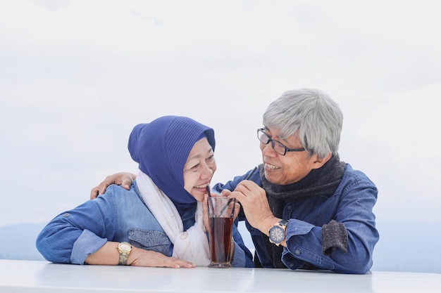 Happy and healthy senior couple sitting and drinking tea together in one glass Never ending love