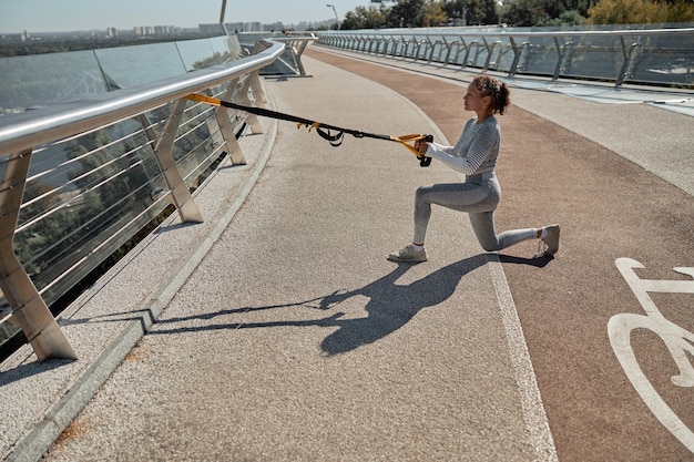 Happy healthy and sporty woman is doing workout trainings in sunny day