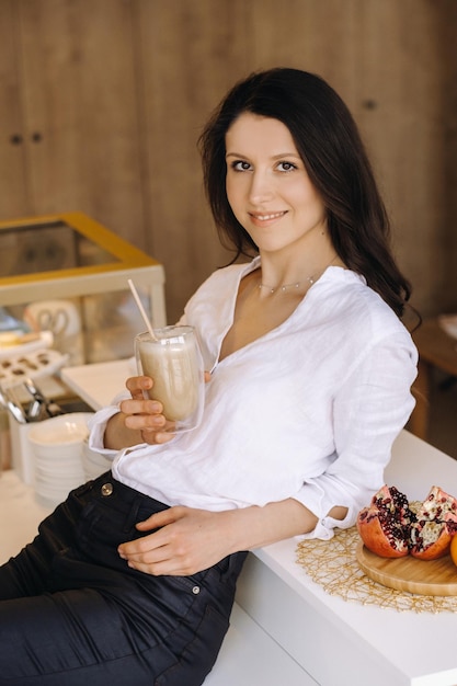 A happy healthy woman is holding a fruit cocktail in her hands standing at home in the kitchenHealthy eating