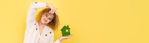 Happy house buyer A young girl holds a model of a green house in her hands The concept of green energy ecology