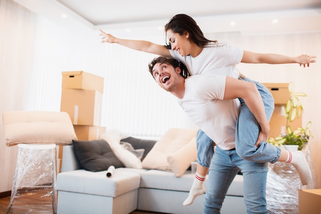 Happy husband and wife have fun swirl sway relocating to own apartment together, relocation concept. Overjoyed young couple dance in living room near cardboard boxes entertain on moving day.